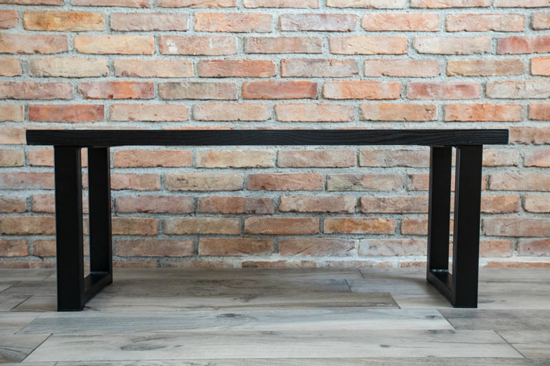 Black wooden spruce bench with a clean, modern design and sturdy legs, perfect for both indoor and outdoor spaces.