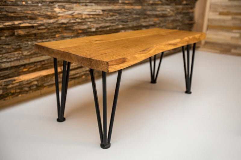 Live edge hairpin oak coffee table with a natural wood finish and sleek metal legs, combining rustic and modern styles.