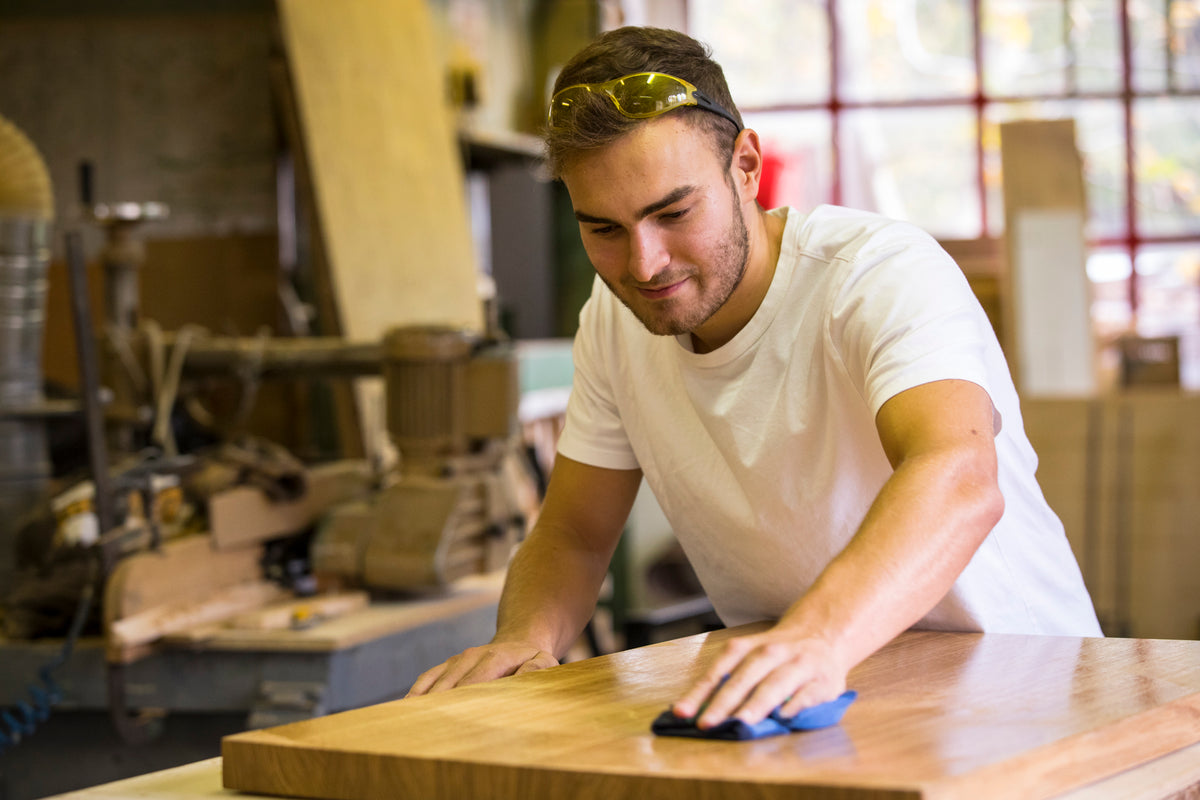 Craftsman hand-finishing a wooden tabletop in the CAPOARTI workshop